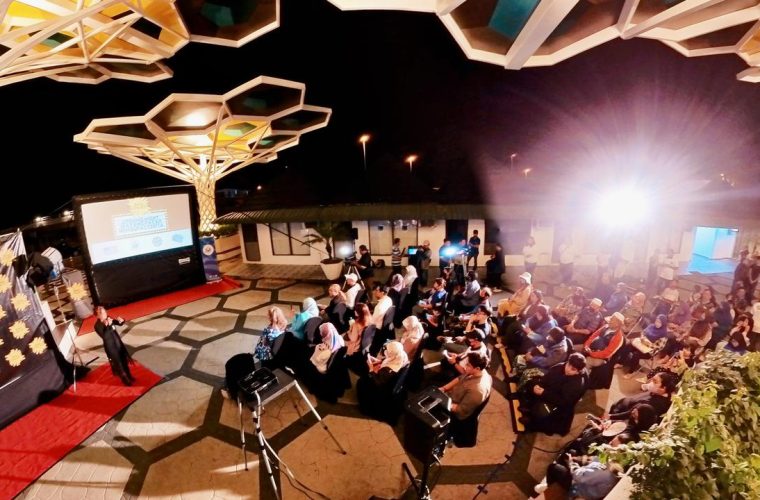 Bezoekers genieten van een filmvertoning onder de sterren op het Museumpark in Rotterdam, met de musea op de achtergrond.